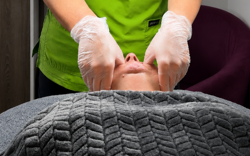 a therapist is carrying our buccal sculpting massage on a clients chin and jawline
