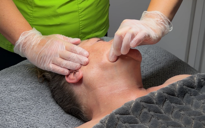 a therapist is carrying our buccal sculpting massage on a clients cheek and jaw line.